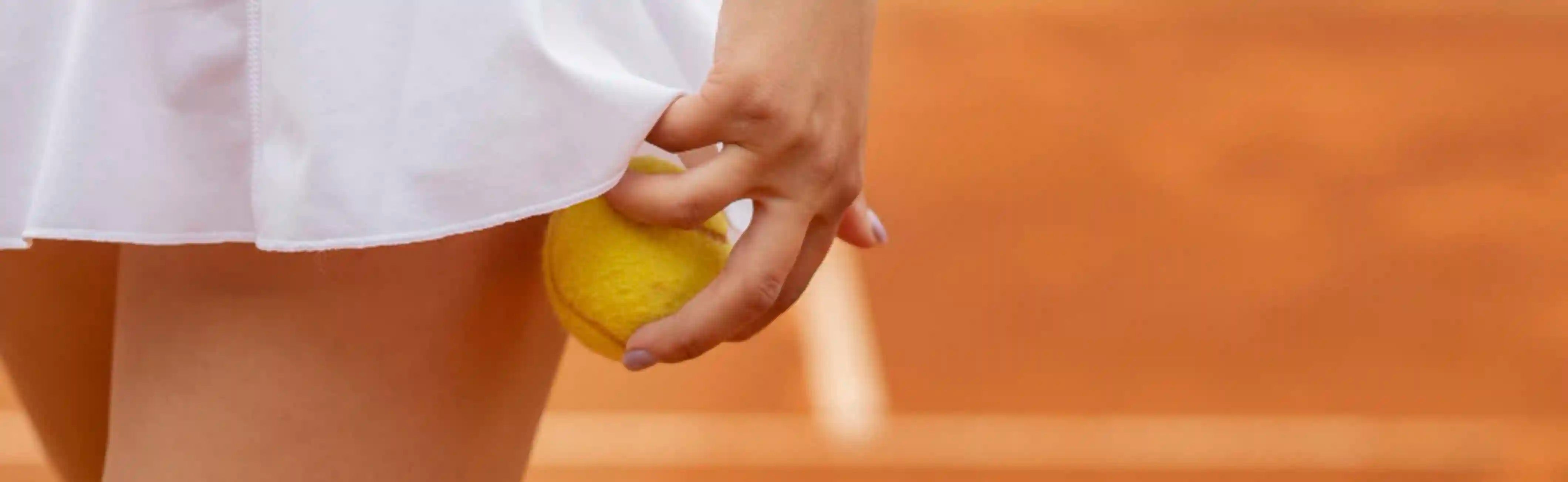 Close-up of padel balls on court surface with racket in background
