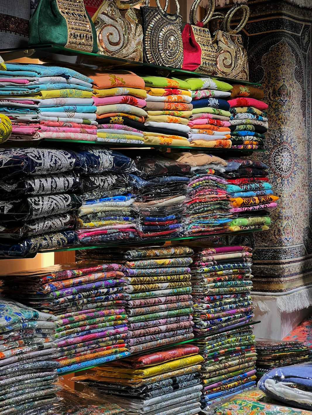Colorful folded fabrics and bags displayed on shelves.